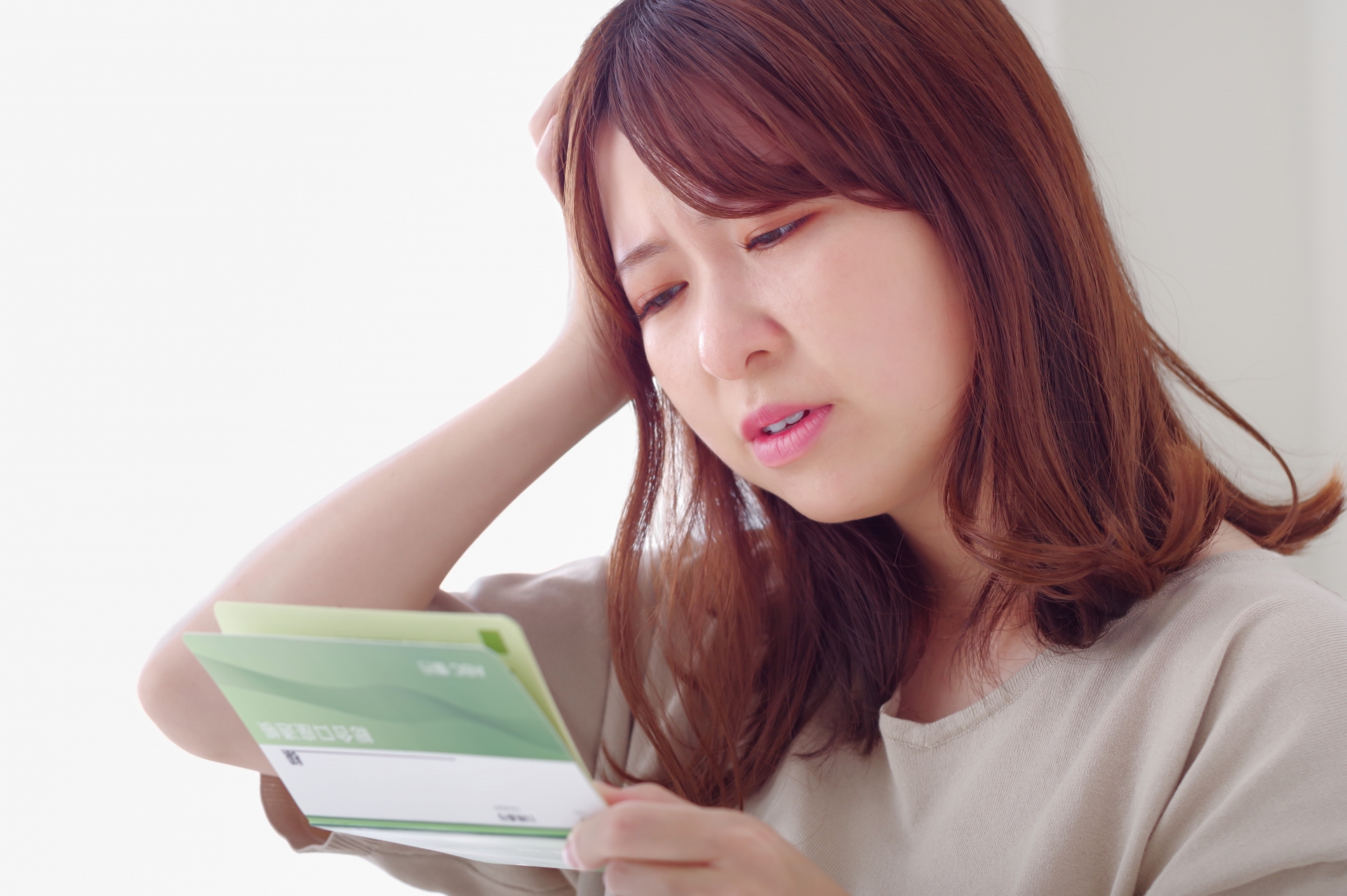 通帳を見ながら浮かない表情をする若い女性