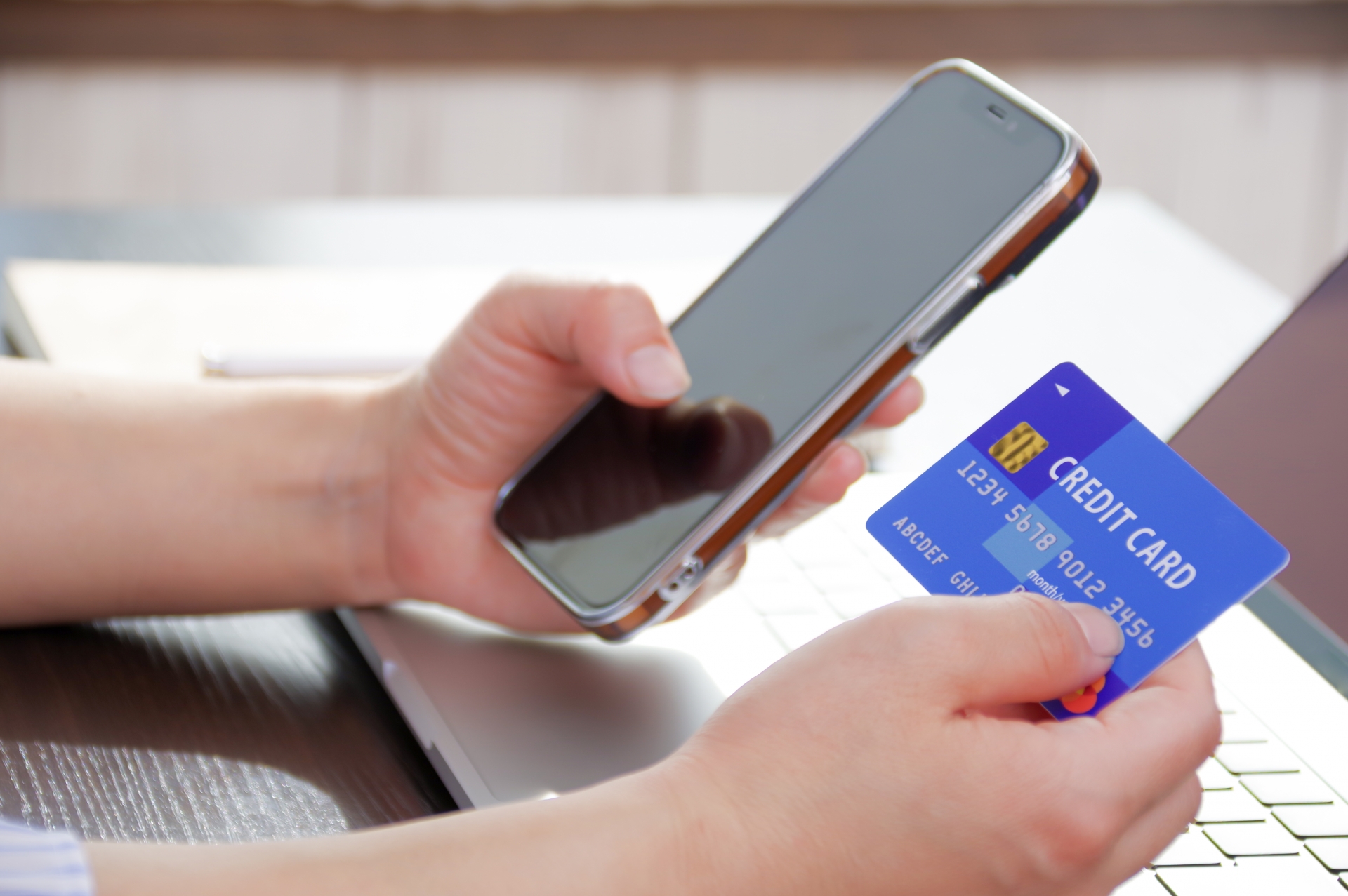 スマホとクレジットカードを手に持つ女性