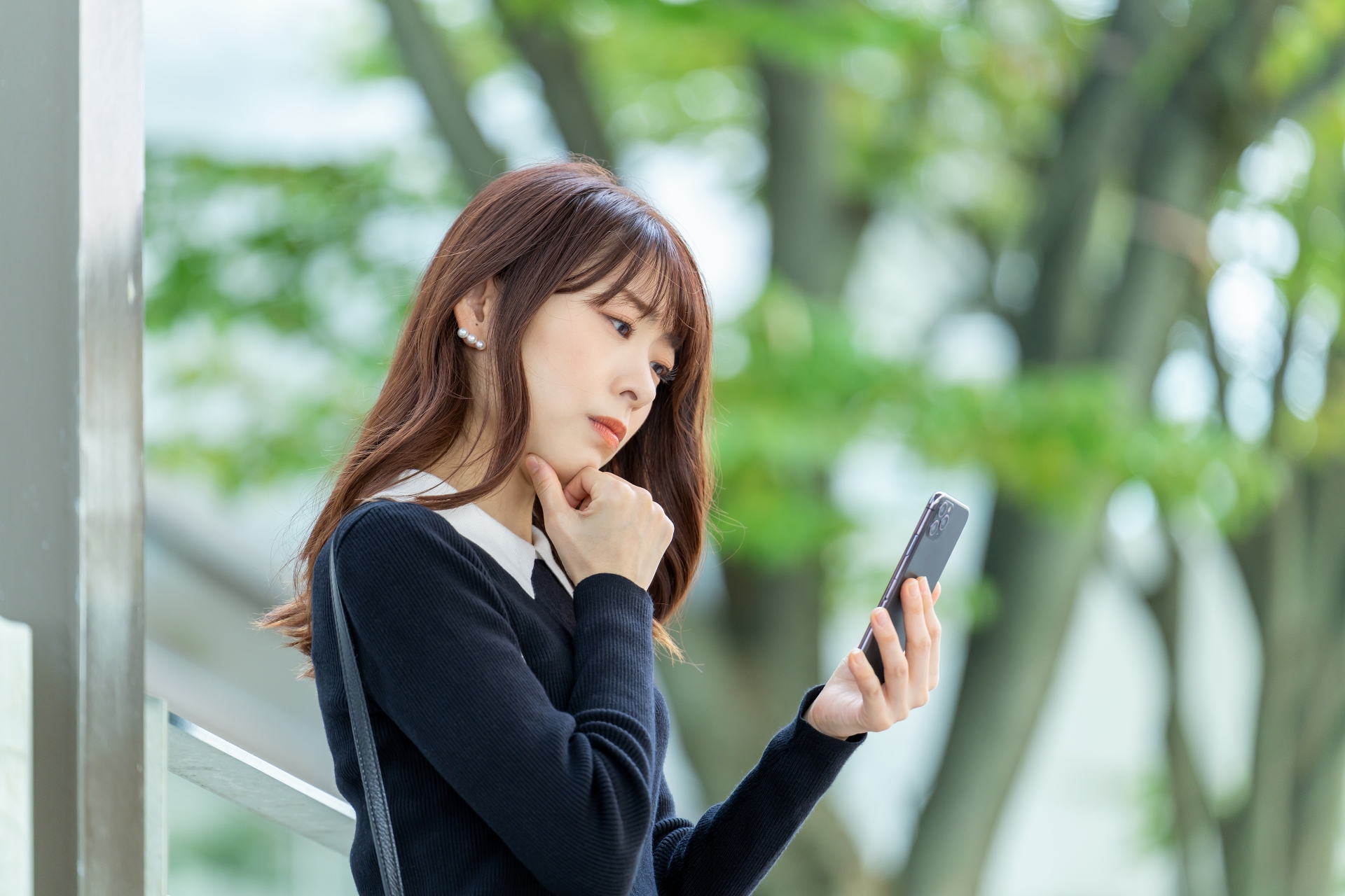 スマホの画面を見て考えるビジネスウーマン